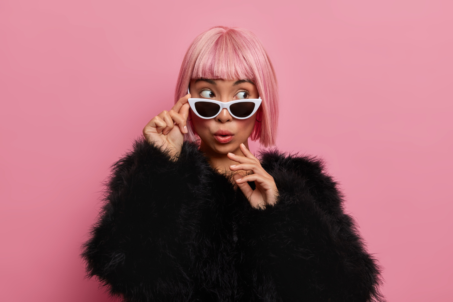 beautiful wondered millennial girl wears pink hair wig sunglasses black fluffy sweater scared see something surprising thrilling aside stands indoor rosy wall people style fashion