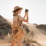 attractive stylish young woman khaki dress desert traveling africa safari wearing hat backpack taking photo vintage camera 285396 9174