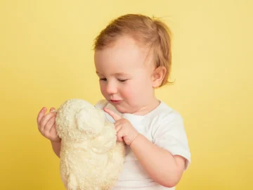little girl with plushie isolated yellow studio wall 155003 29830