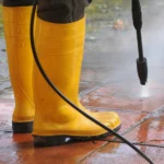 person wearing yellow rubber boots with high pressure water nozzle cleaning dirt tiles 181624 23652