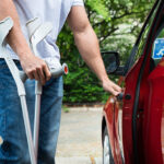 Man with crutches opening car door